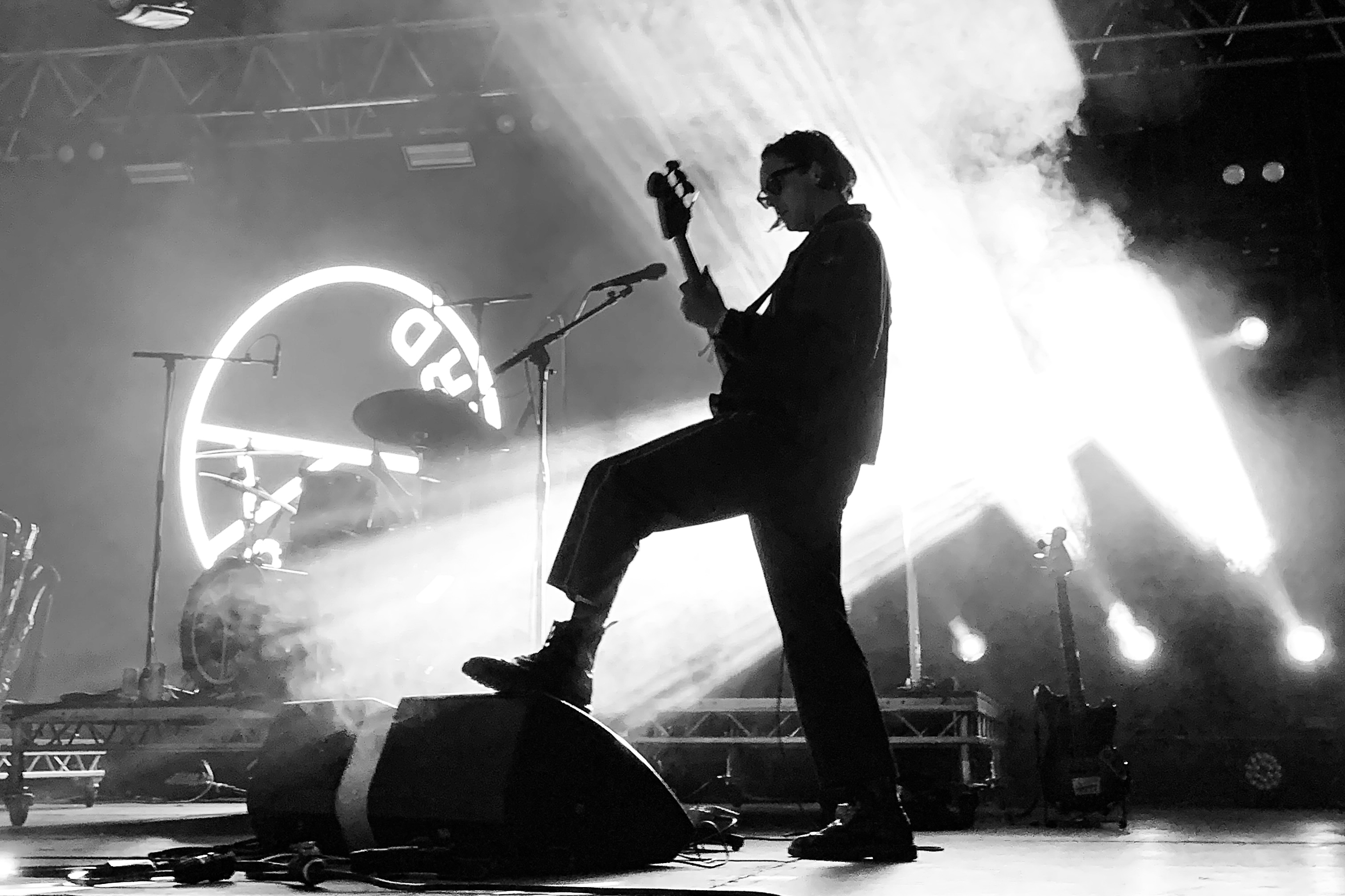 Silhouette of Ryan Needham of Yard Act playing bass with one foot on a speaker at Boardmasters 2023 on the Land of Saints stage