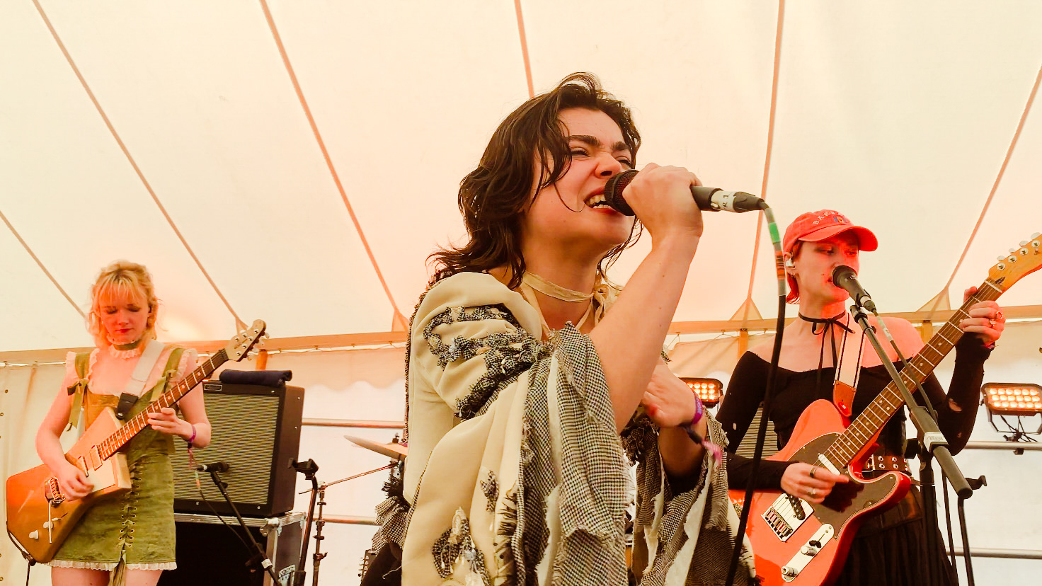 The Last Dinner Party playing at Boardmasters, Cornwall on The Cove stage. From left to right Emily Roberts playing rhythm guitar, Abigail Morris singing and Lizzie Mayland playing guitar.