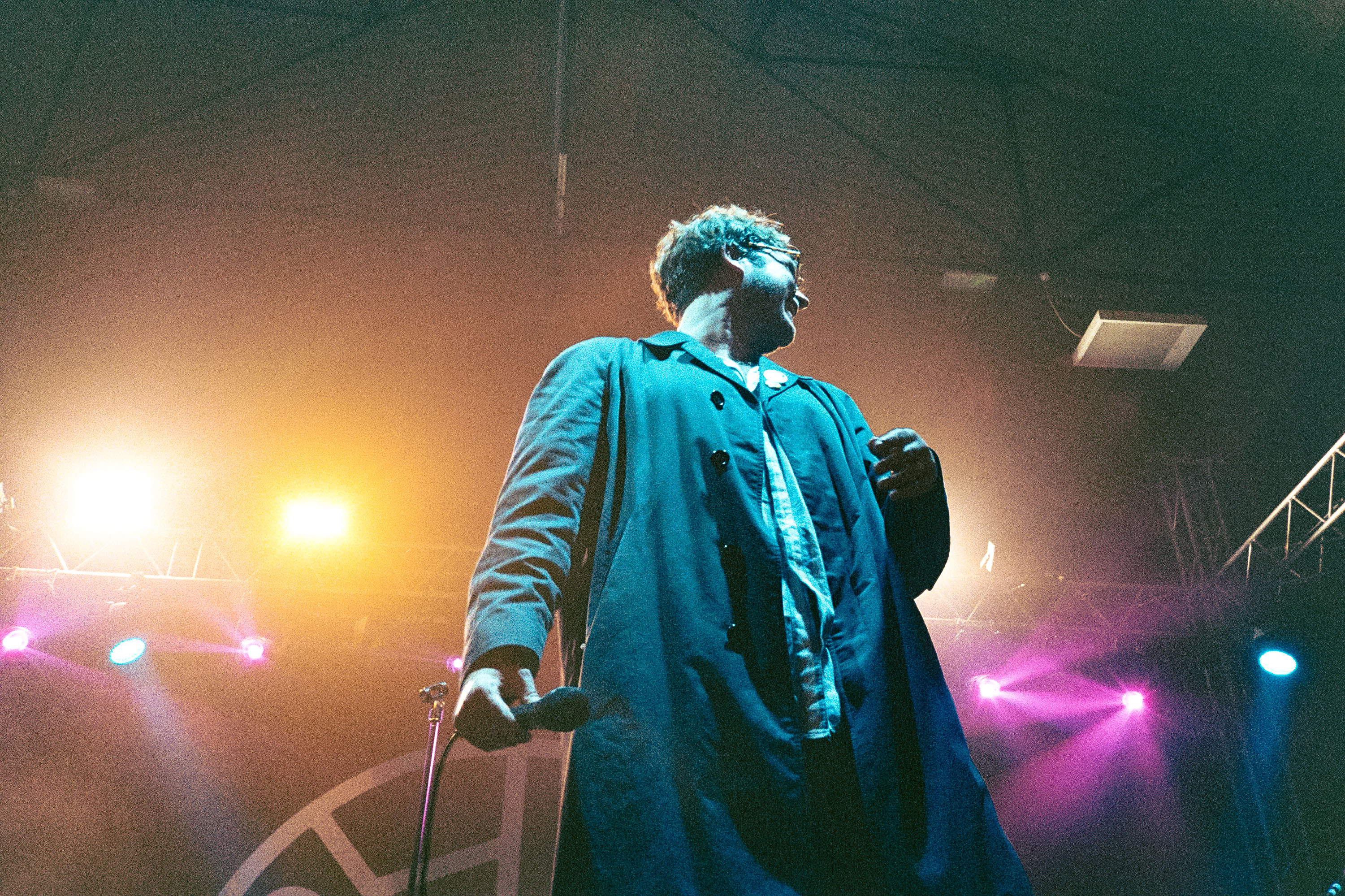 James Smith of Yard Act turned to the side and smiling while holding a microphone at his side at Marble Factory Bristol November 26th 2022